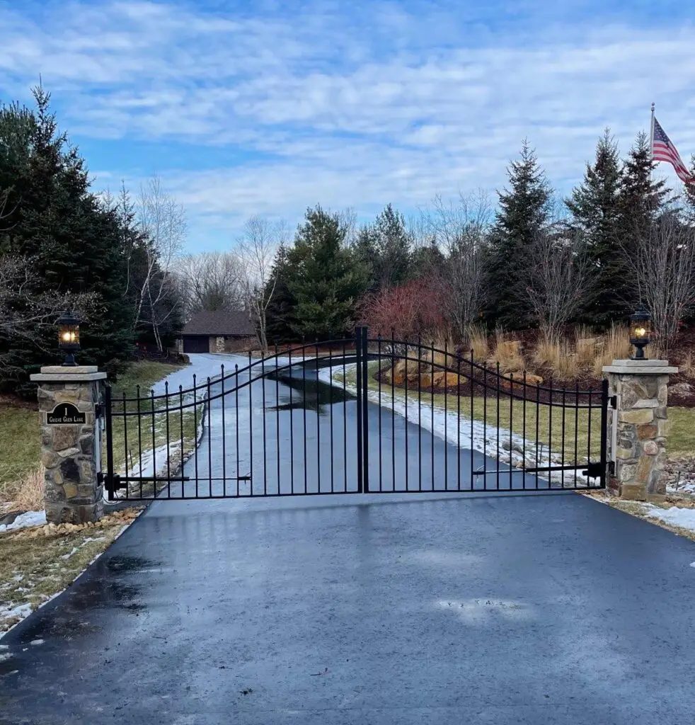 a driveway with a gate and flags - custom ornamental iron gates